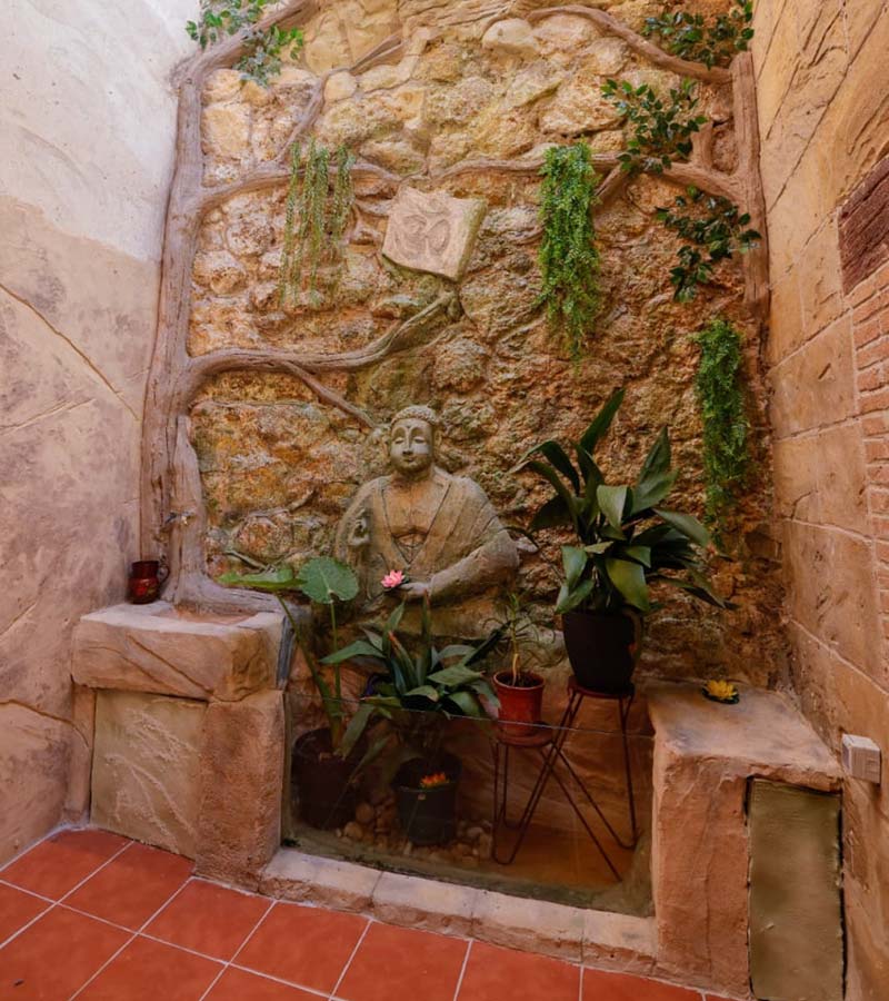 Estatua de Buda esculpida en pared de piedra con plantas en el patio interior de la antigua posada Casa Torre del Carmen en Cazorla Estatua de Buda esculpida en pared de piedra con plantas en el patio interior de la antigua posada Casa Torre del Carmen en Cazorla